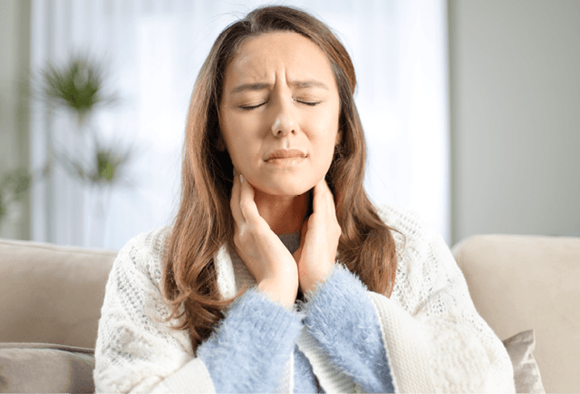 Woman holding her neck due to a sore throat