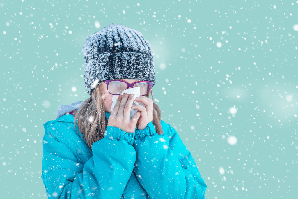 Girl in the snow with a tissue to her nose